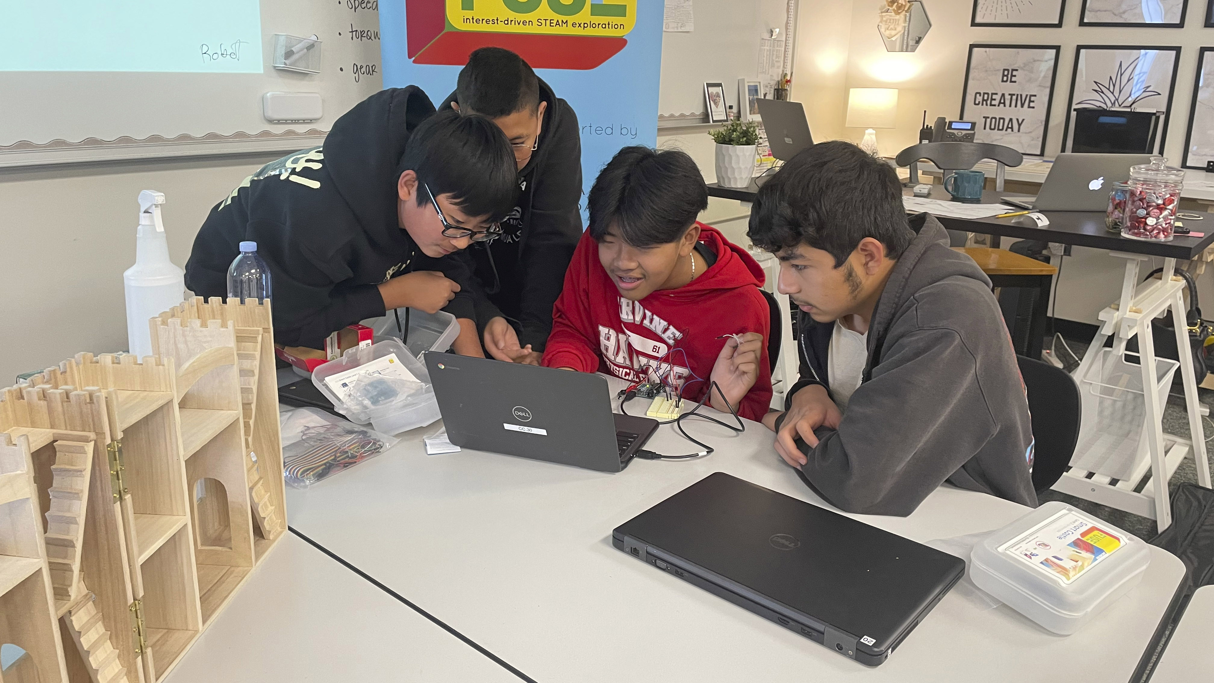 students gather around a computer and kit